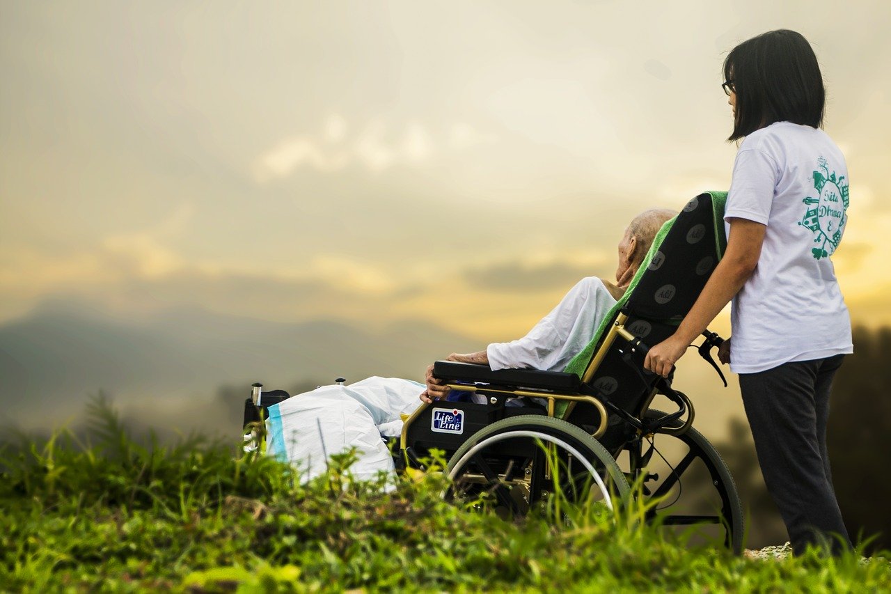 woman pushing a woman in wheelchair outdoors